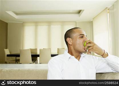 Young man eating a granny smith apple