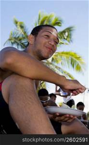 Young man eating at beach party