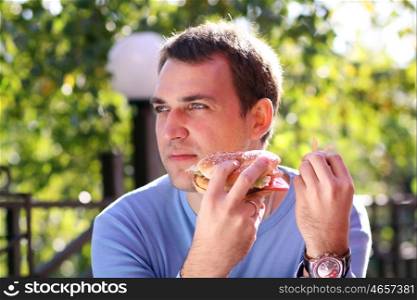 Young man eating burger in fast food