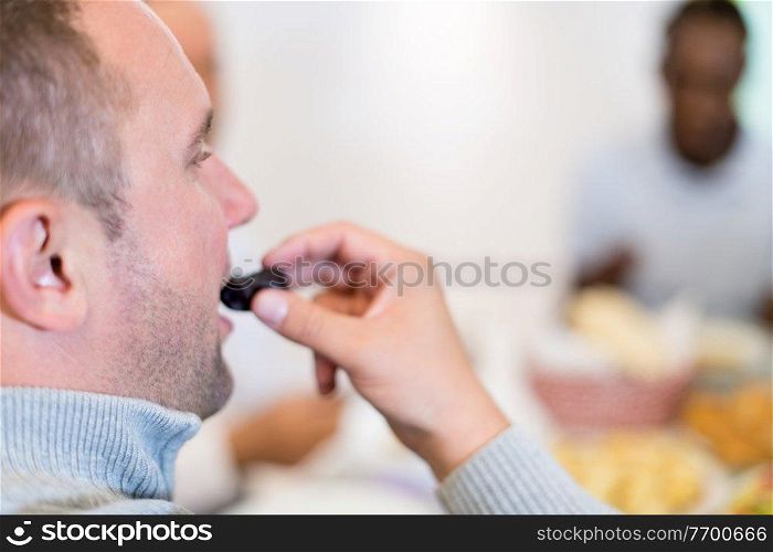 young man eating dates with modern multiethnic muslim family while enjoying iftar dinner together during a ramadan feast at home