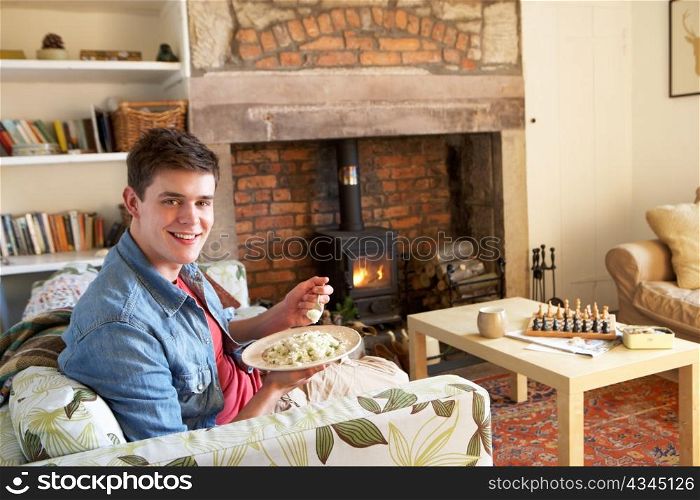 Young man eating meal by fire