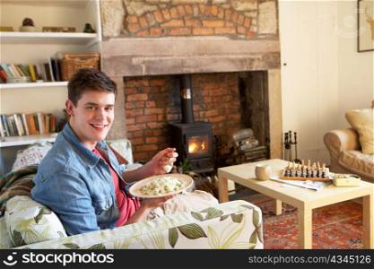 Young man eating meal by fire