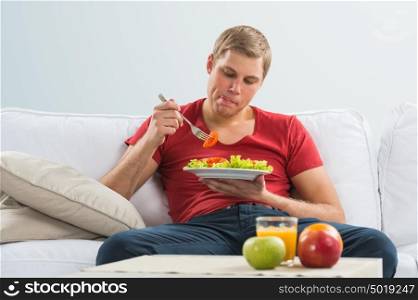 Young man eating vegetarian salad with appetite