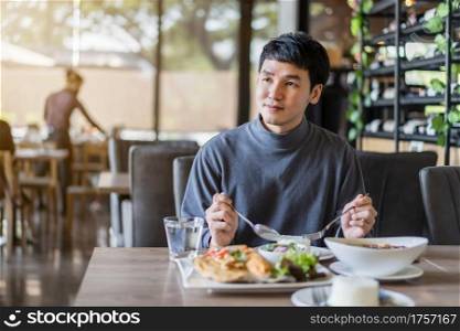 young man eating with food in restaurant