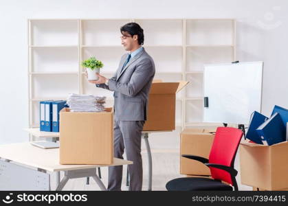 Young man employee with boxes in the office 