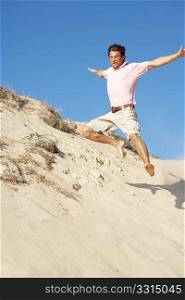 Young Man Enjoying Beach Holiday Running Down Dune