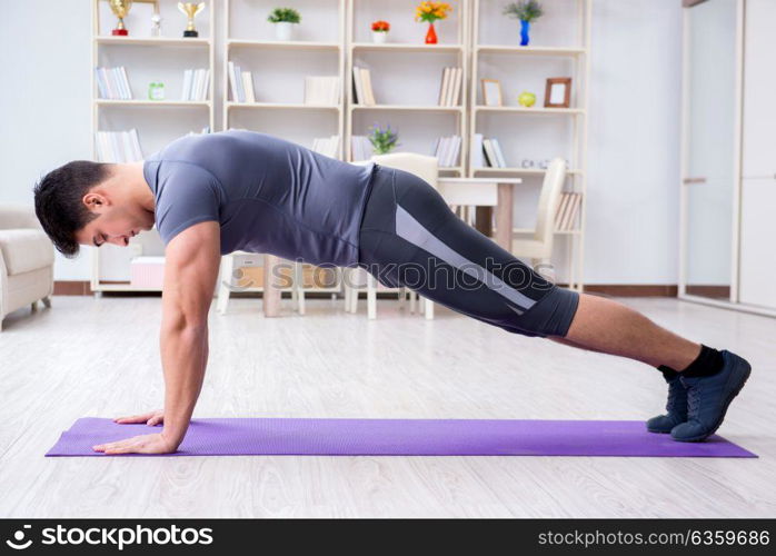 Young man exercising at home in sports and healthy lifestyle concept. Young man exercising at home in sports and healthy lifestyle con