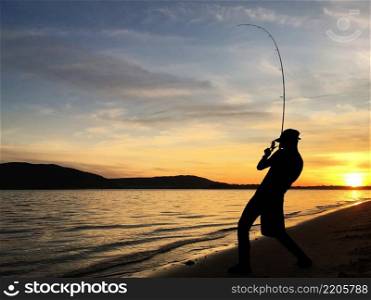 Young man fishing on a lake at sunset. Young man fishing at sunset