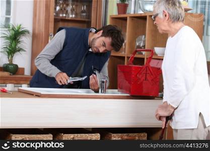 young man fixing faucet older woman