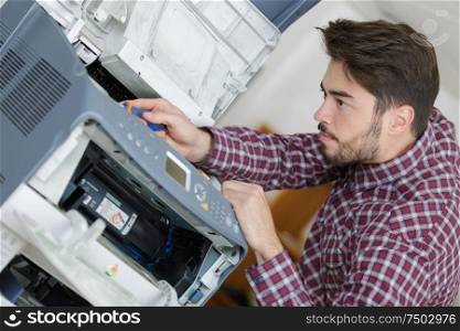 young man fixing printer