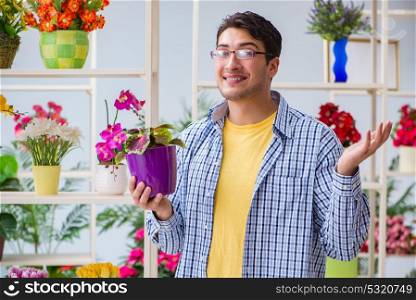 Young man florist working in a flower shop