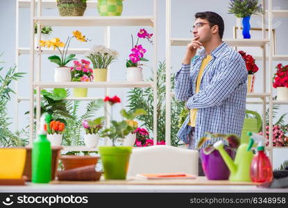 Young man florist working in a flower shop