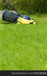 Young man gardener using lawn mower at sunny day