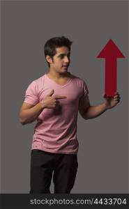 Young man gesturing to arrow sign