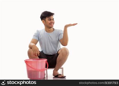 Young man gesturing while washing clothes by hand