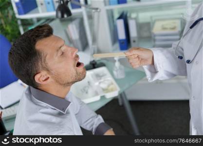 young man getting his throat checked by male doctor