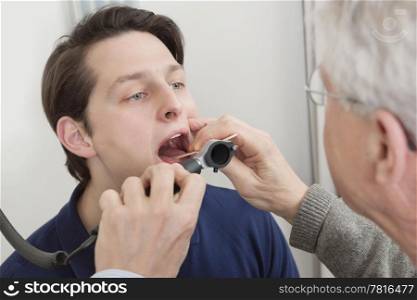 Young man getting his throat checked by male doctor at clinic