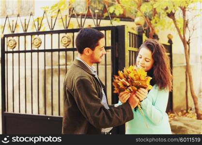 Young man giving a bouquet of autumn leaves