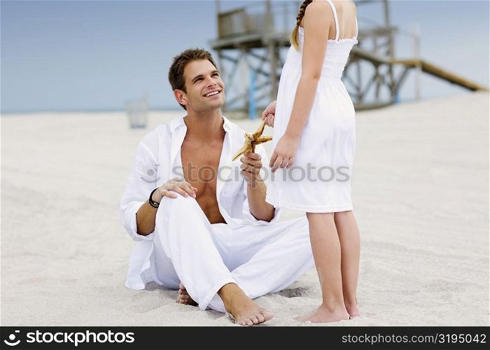 Young man giving a starfish to his daughter