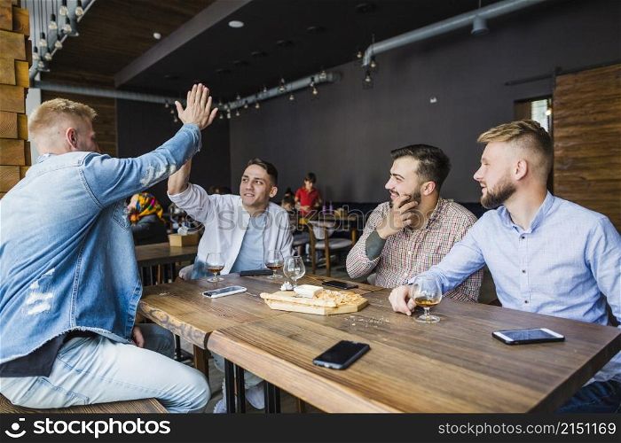 young man giving high five his friends restaurant