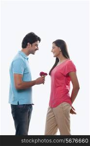 Young man giving rose to woman over white background