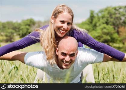 Young man giving shoulder ride to her girlfriend in outdoors