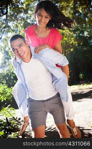 Young man giving woman piggy back