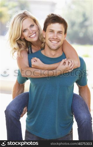 Young Man Giving Woman Piggyback Outdoors
