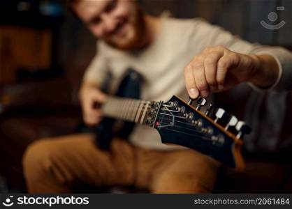 Young man guitarist tune guitar before playing. Music lesson creative hobby. Selective focus closeup. Young man guitarist tune guitar before playing