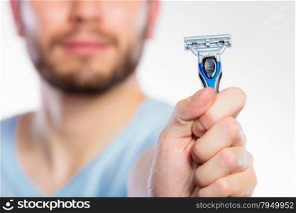 Young man guy with beard showing disposable blue razor blade, studio shot on white background. Cropped image