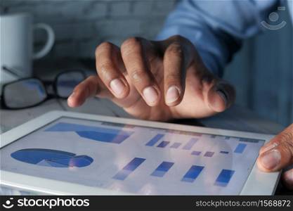 young man hand analyzing financial data and chart on digital tablet.. young man hand analyzing financial data and chart on digital tablet