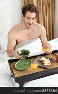 Young man having breakfast in bed