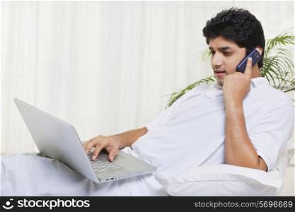 Young man having conversation while using laptop at home
