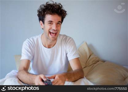 Young man having fun playing games in the bed.
