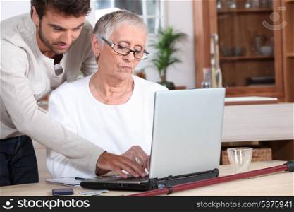 Young man helping a senior with a laptop computer