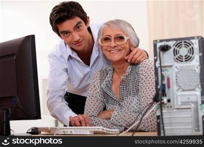 Young man helping an elderly lady use a computer
