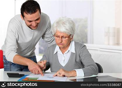 Young man helping elderly woman with paperwork