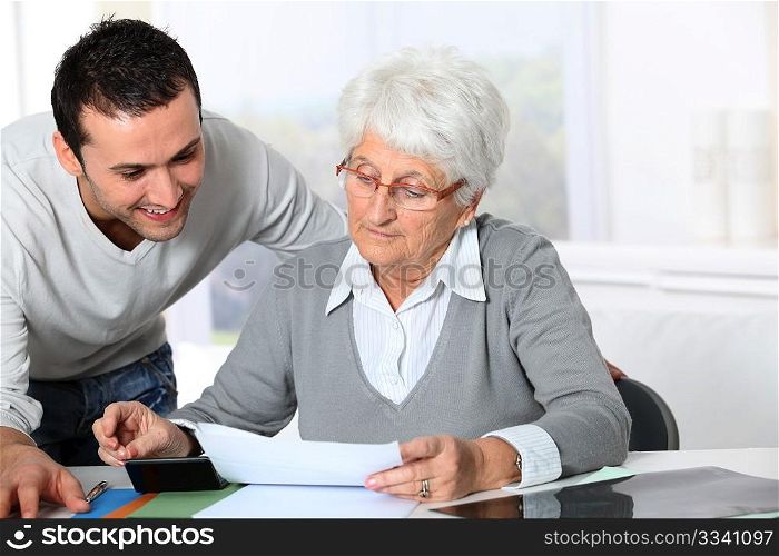 Young man helping elderly woman with paperwork