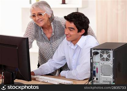 Young man helping his grandma with her computer.