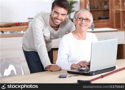 Young man helping senior woman with a laptop compute