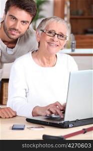 Young man helping senior woman with a laptop computer