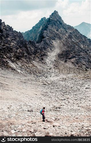 Young man hiking alone along a rocky trail in the mountains