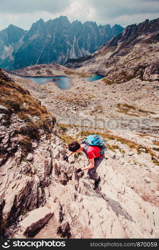 Young man hiking alone along a rocky trail in the mountains