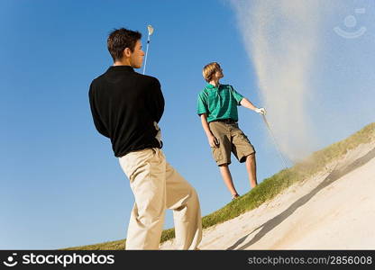 Young Man Hitting Ball in Sand Trap