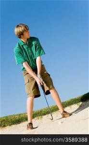 Young Man Hitting Ball in Sand Trap