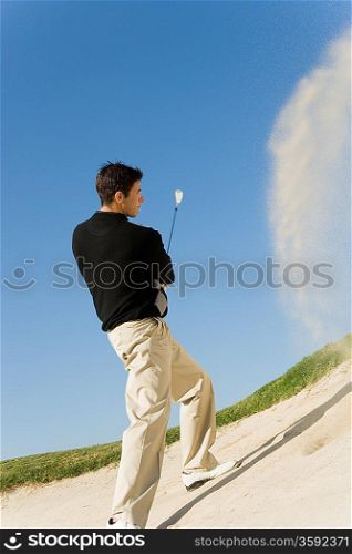 Young Man Hitting Ball out of Sand Trap