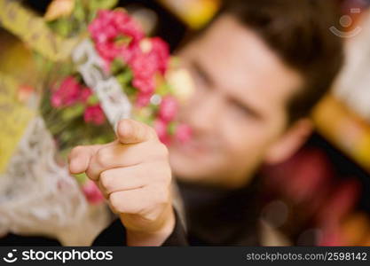 Young man holding a bouquet of flowers and pointing
