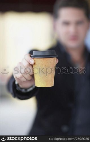 Young man holding a disposable glass