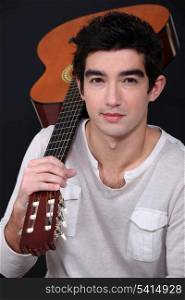 young man holding a guitar on his shoulder