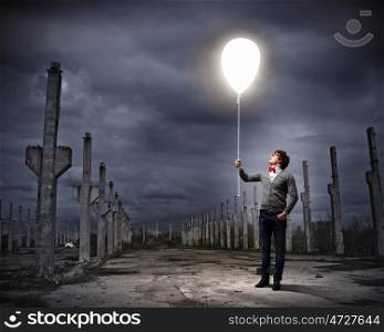 Young man holding a light. Young man holding a light at his hands against polluted and ruined landscape